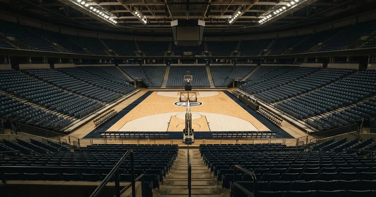 Eine leere Basketballhalle von einer oberen Tribünenreihe aus gesehen, Parkett und Körbe im Licht der Hallenstrahler.