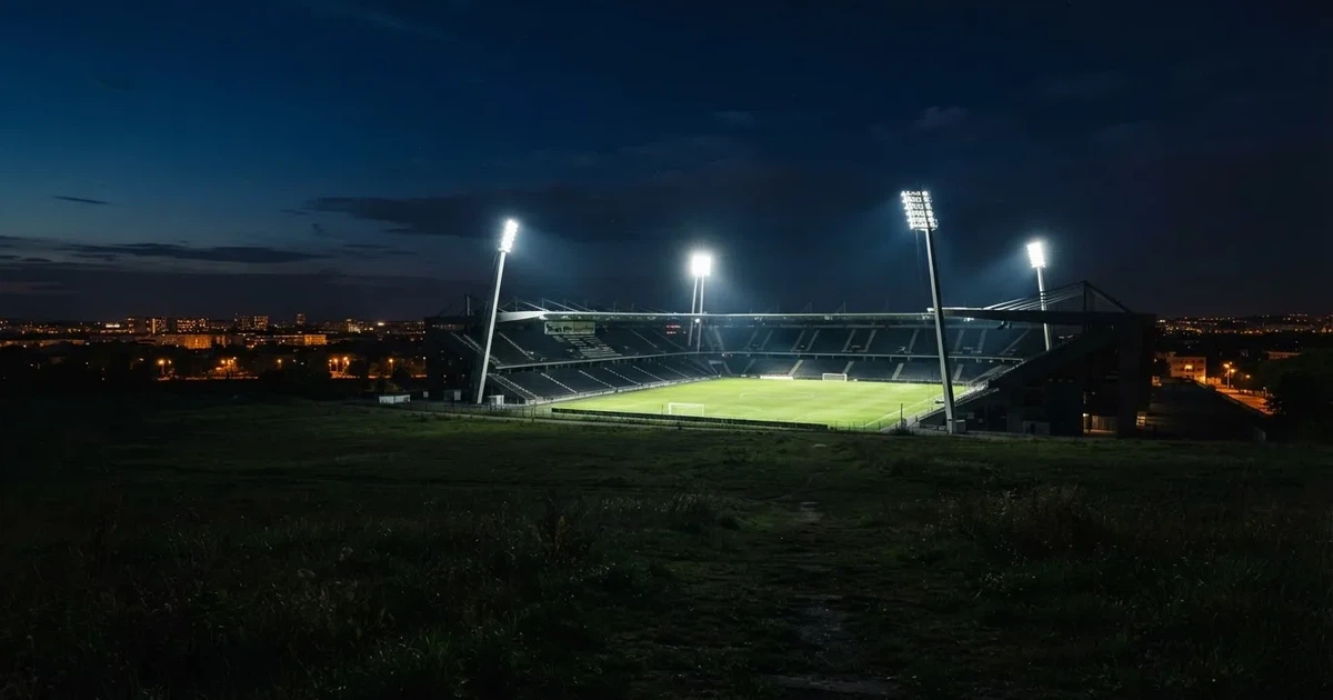 Ein Stadion bei Nacht unter Flutlicht aus der Ferne gesehen, der Rasen ist hell erleuchtet, keine erkennbaren Personen.