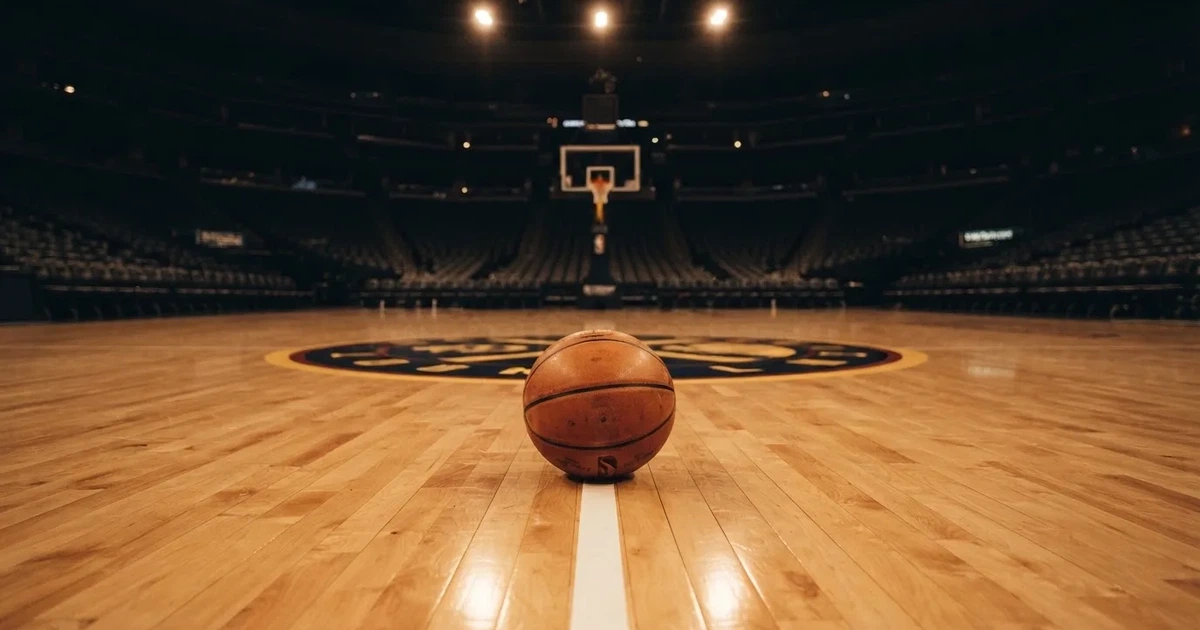 Ein Basketball liegt auf dem Parkettboden einer leeren Arena, Scheinwerfer werfen Licht auf die Mittellinie.